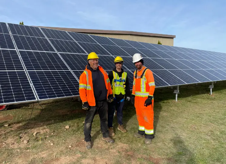 Three men standing front of solar array by Natural Forces Solar